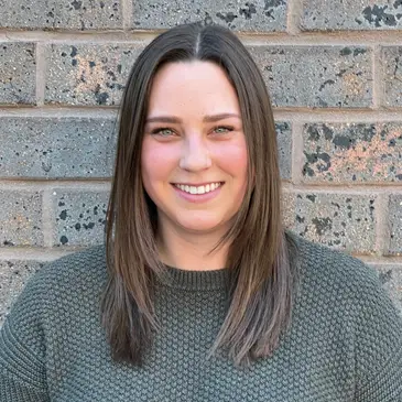 A woman standing in front of a brick wall.