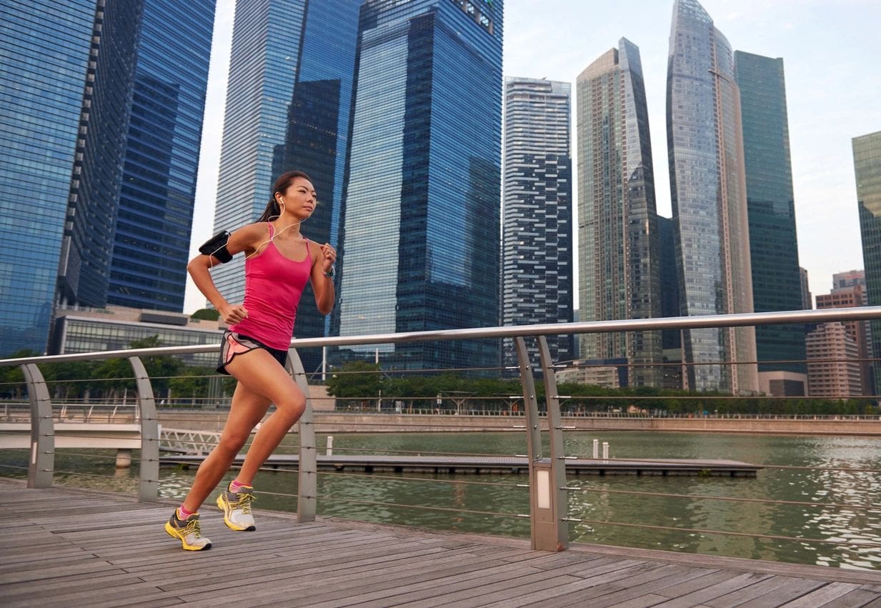 asian chinese sporty running woman working out running outdoors along urban city harbor sidewalk morning