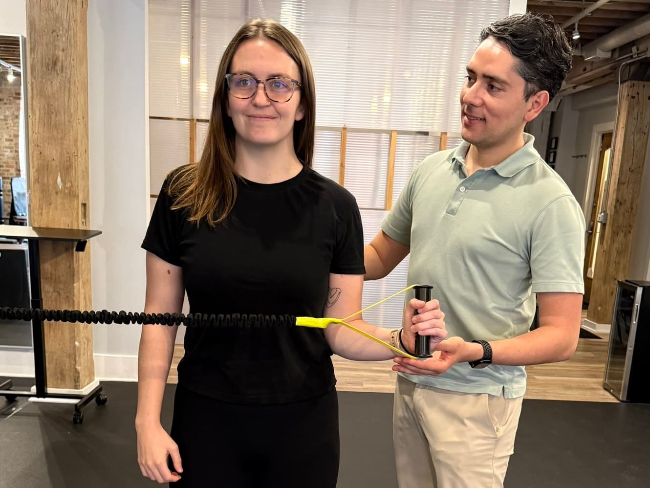 Physical therapist guiding a resistance band external rotation exercise for rotator cuff repair rehab in Chicago
