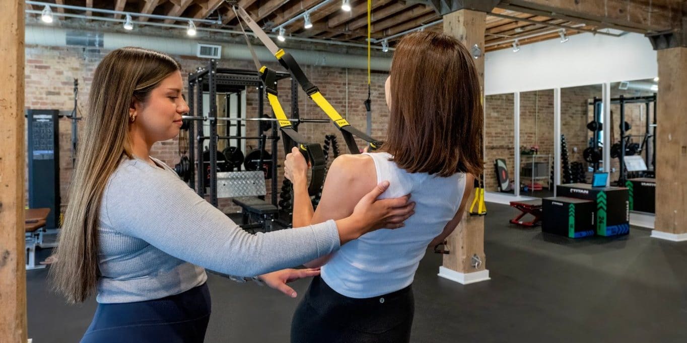 Physical therapist guiding shoulder blade control during a TRX row at Dynamic Physical Therapy Chicago